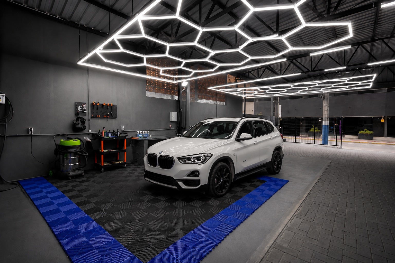 Studio MyiCAR com iluminação hexagonal e BMW branca em detalhamento